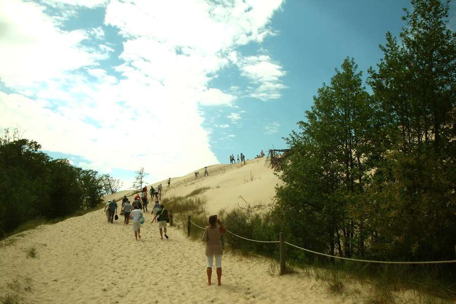Visitors climbing the sand path toward the Lacka dune in Slowinski National Park