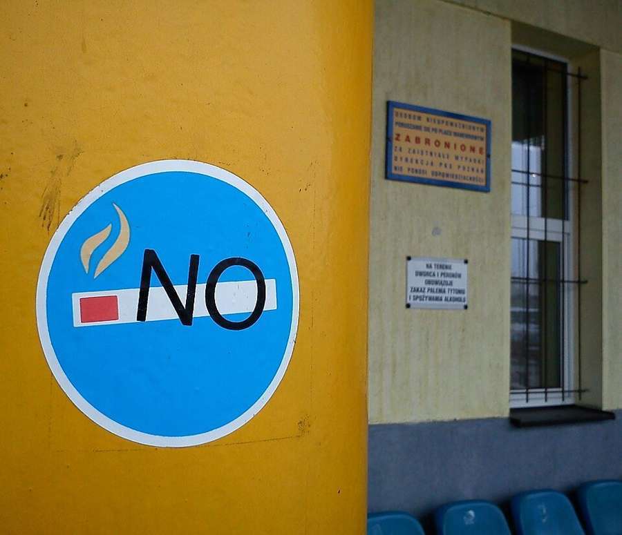 A no-smoking sign on a yellow wall at a bus stop in Poznań, Poland