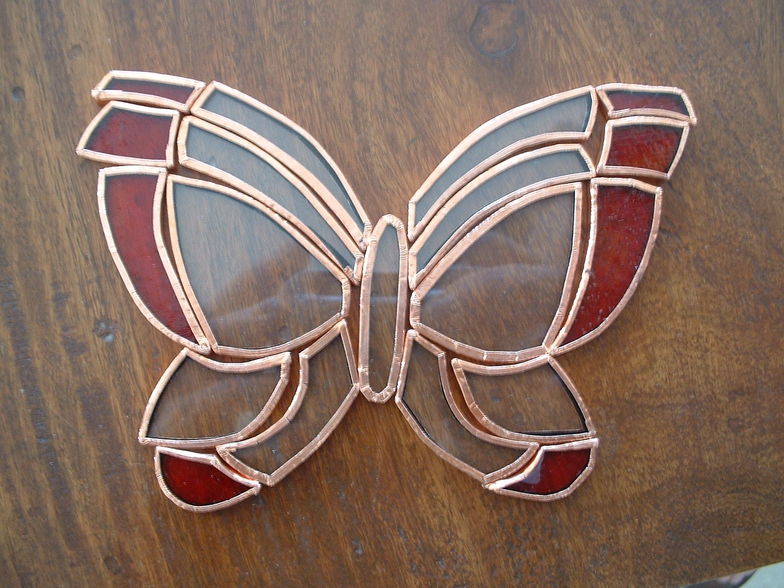 Red and clear butterfly-shaped glass pieces edged in copper foil before soldering