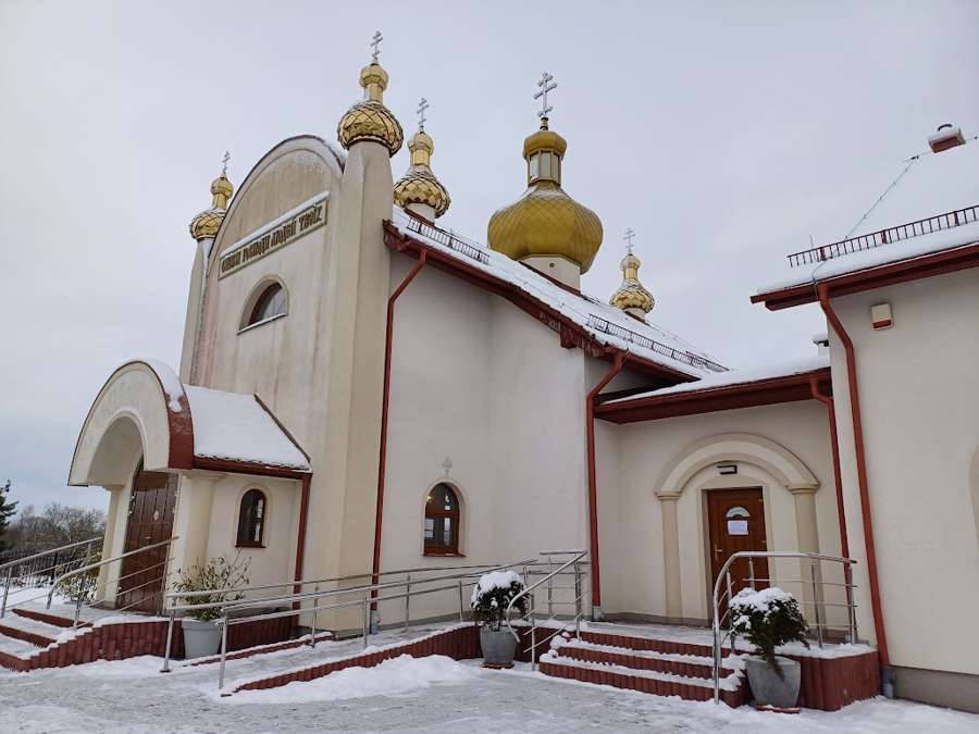 A white church with golden domes in Szczecinek covered by a light layer of snow