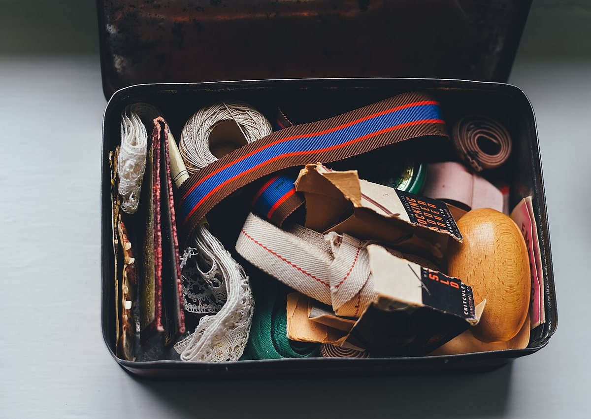 Open vintage sewing box containing thread, buttons and other sewing supplies