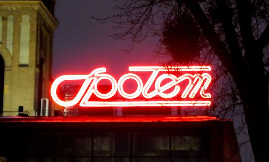 The red neon Spolem sign glowing at night in Warsaw