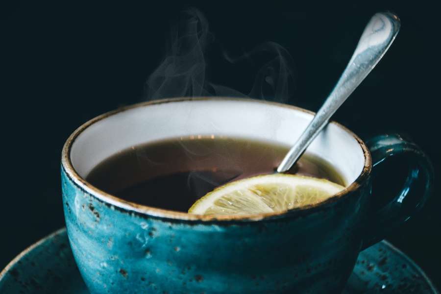 A steaming cup of black tea with a slice of lemon
