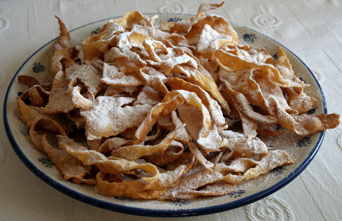 A plate of faworki, crisp bow-shaped Polish carnival pastries dusted with icing sugar