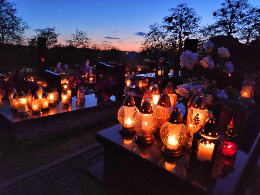 Grave candles burning at a Polish cemetery at dusk on All Saints' Day