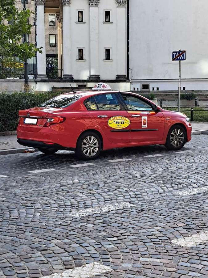 Red Fiat Tipo taxi parked at a TAXI sign in Warsaw