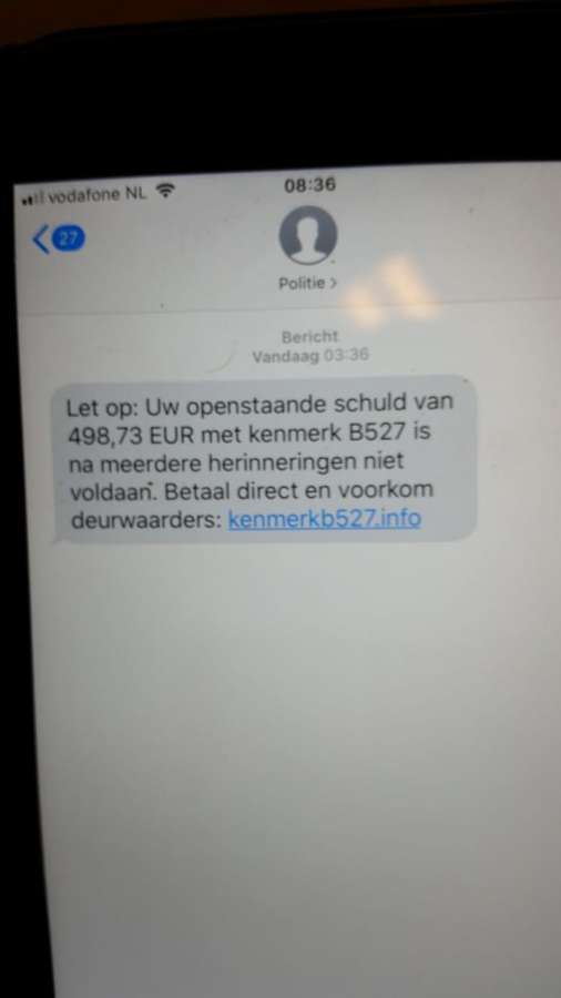 A phone showing a scam SMS impersonating police and demanding payment through a link