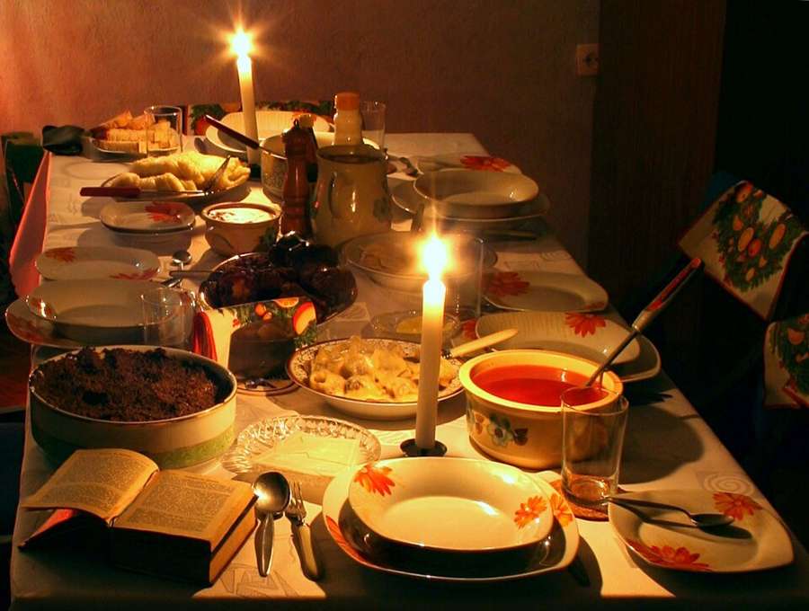 A candlelit Wigilia supper table with traditional dishes