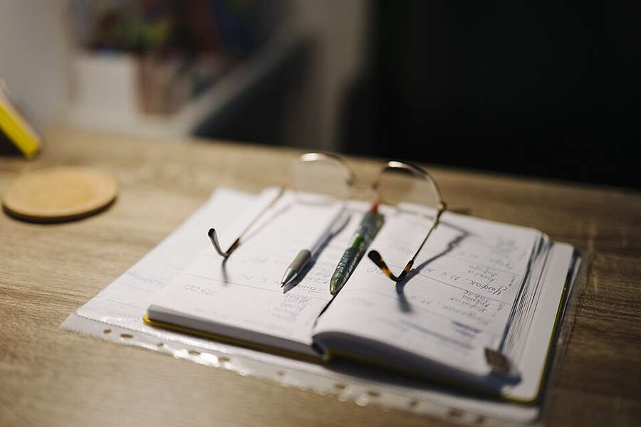 Reading glasses resting on an open notebook beside pens, an illustrative desk photograph