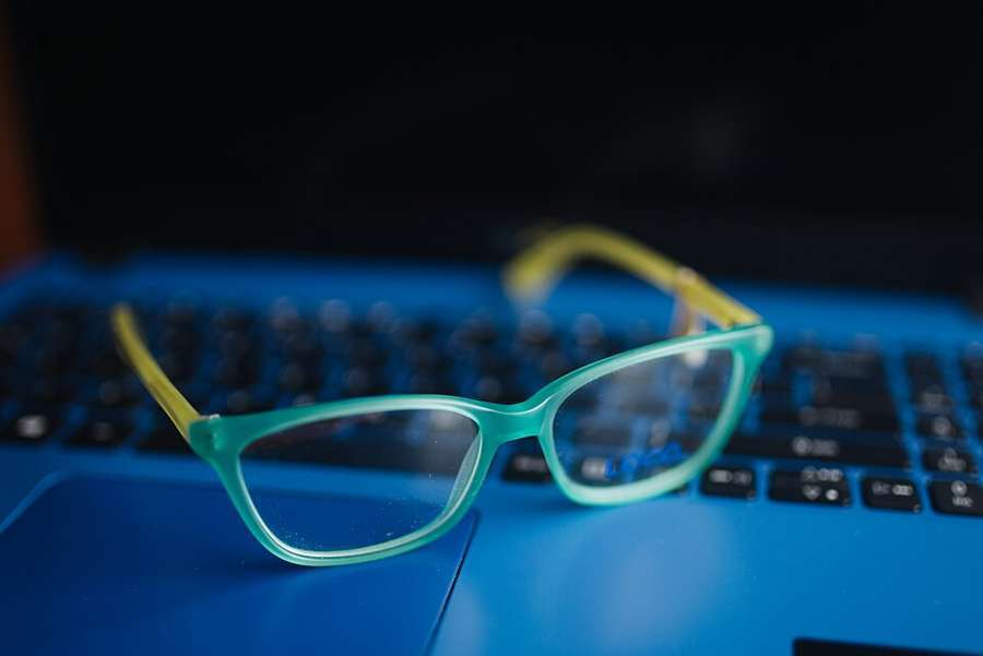 Illustrative corrective glasses resting on a blue laptop keyboard