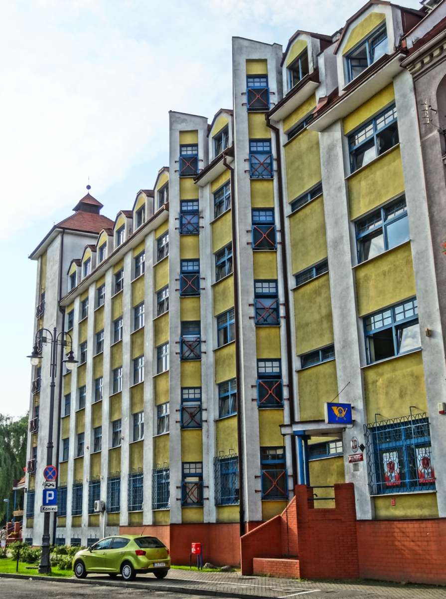 Side view of a tall ZUS social insurance office building with yellow facade