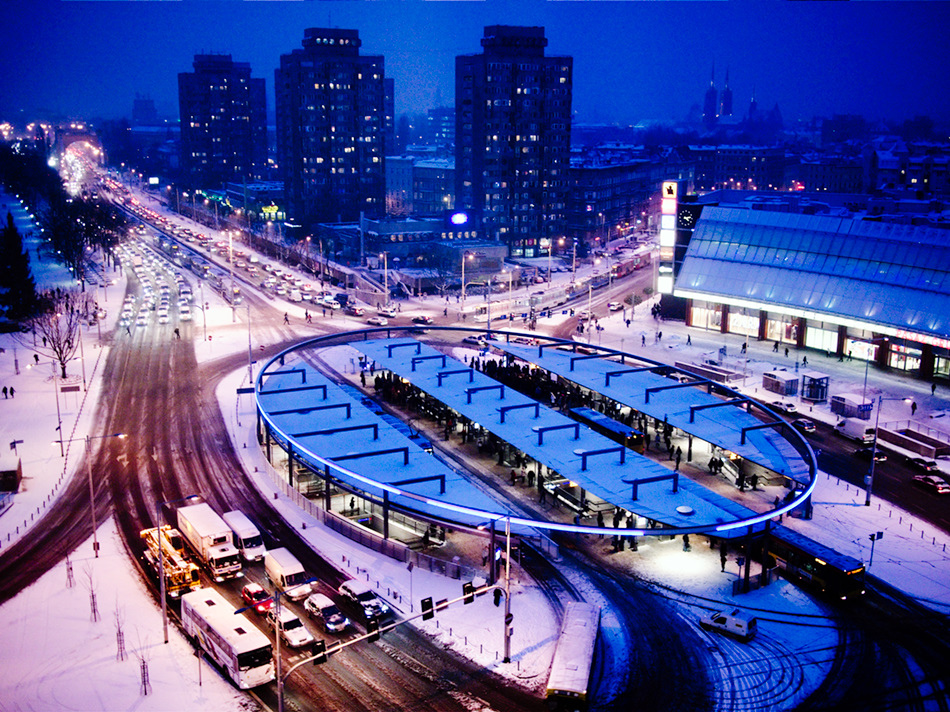 Plac Grunwaldzki in Wrocław under snow at dusk, with the circular tram and bus loop lit up in blue