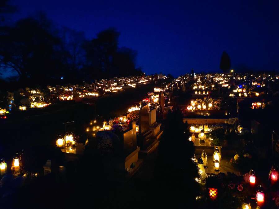 A hillside cemetery in Poland glowing with hundreds of znicz candle lanterns on All Saints' evening